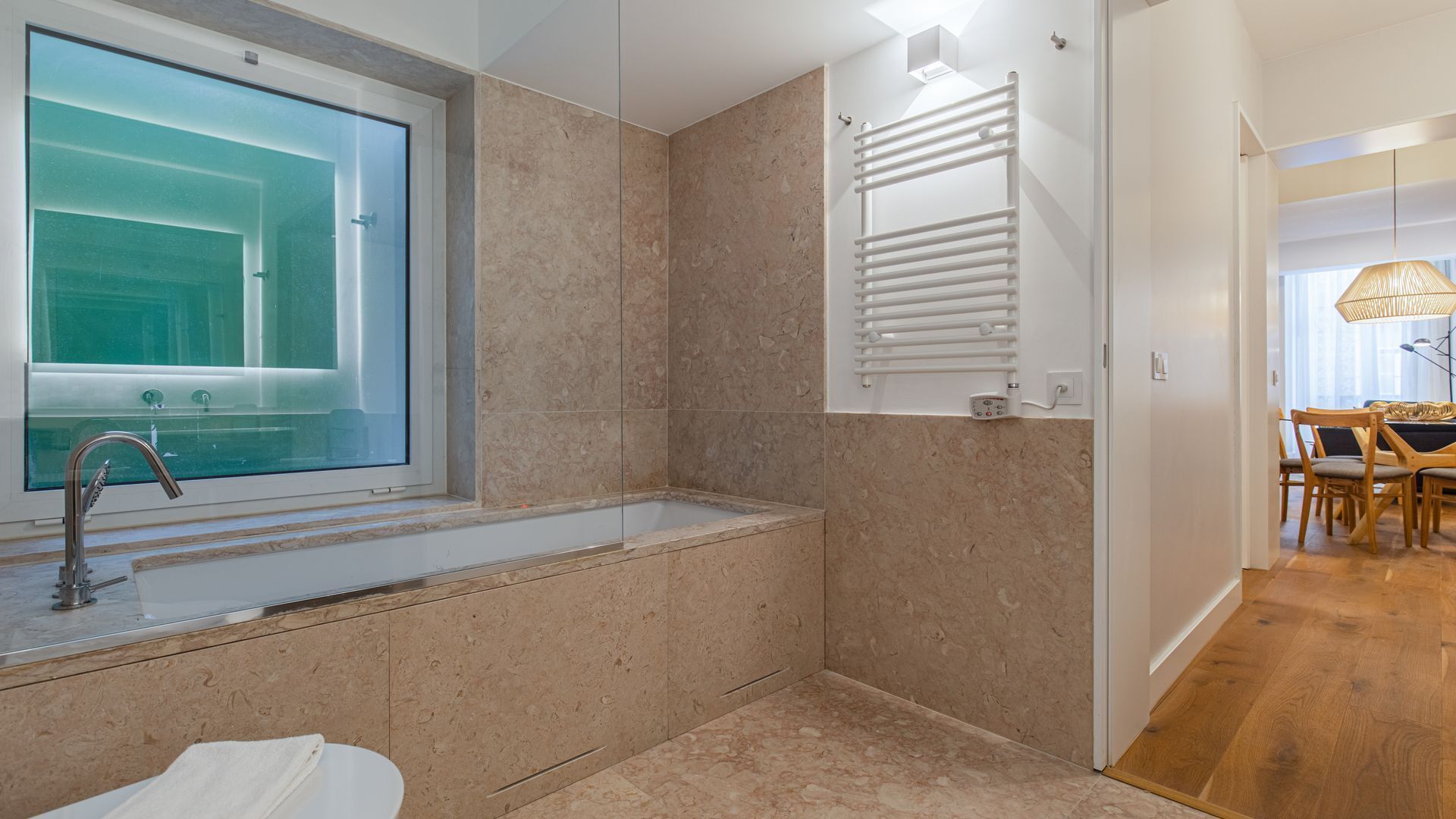 Un baño moderno con cabina de ducha de vidrio, lavamanos empotrado y un perchero para toallas.