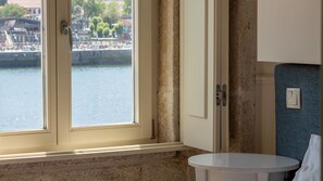 A bathroom with a window overlooking a river, a sink, and a towel rack.