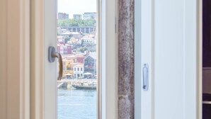 Une vue à travers une porte, donnant sur un paysage urbain avec des bâtiments, un pont et une étendue d’eau.