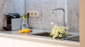 A kitchen with a sink, a coffee machine, and a vase with flowers on the counter.