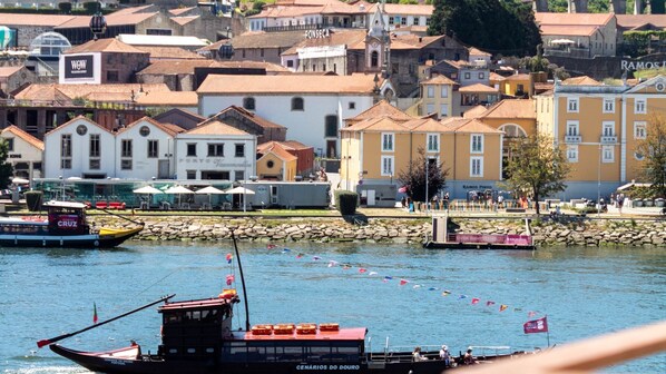 Vista al agua con barcos, un muro de piedra y edificios con señalización.