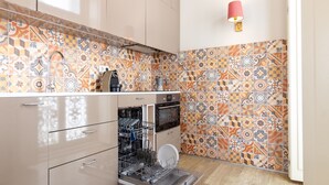 Een keuken met betegelde vloer, een vaatwasser en een koffieapparaat.