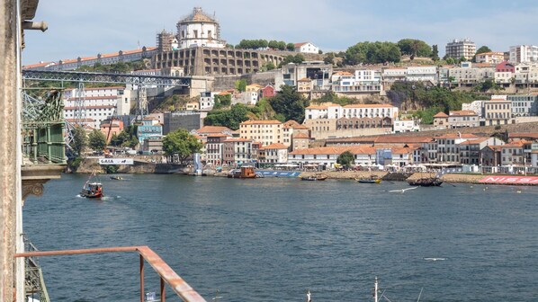 Paisagem urbana à beira do rio, com edifícios históricos, uma ponte e barcos.
