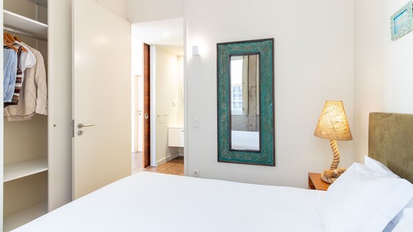 A hotel room with a bed, a bedside lamp, a wardrobe, and a mirror on the wall.