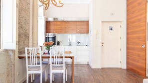 Eine moderne Küche mit weißen Schränken, einem Esstisch mit Stühlen und Holzboden.