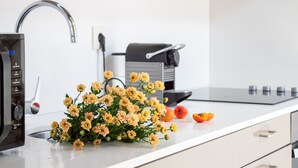 A modern kitchen with a sink, a coffee machine, and a decorative flower arrangement. - Purple Oporto Home River Front - Ribeira (Vila Nova de Gaia)