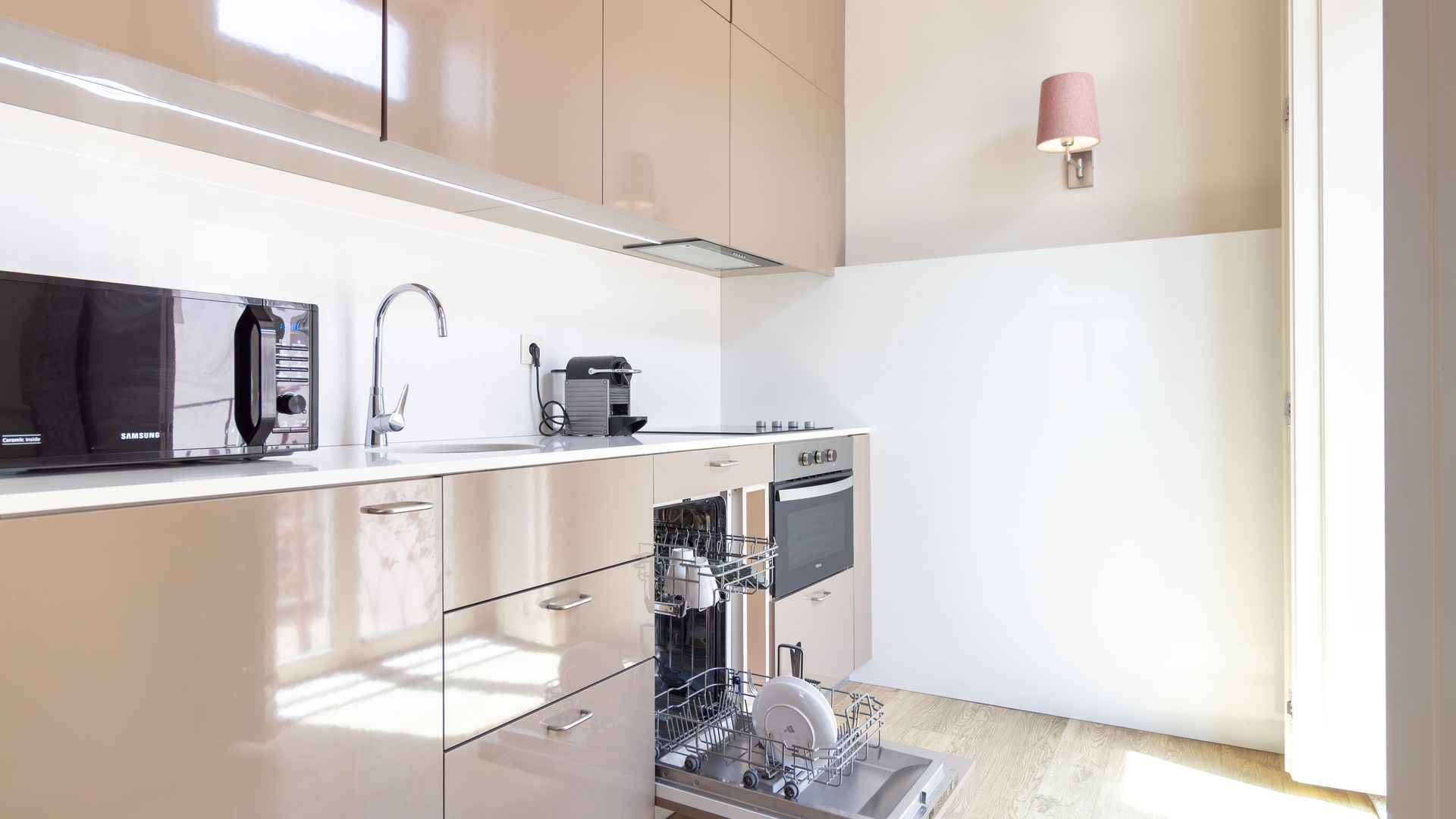 Cozinha moderna equipada com micro-ondas, pia, cafeteira e máquina de lavar louça.