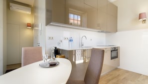 A modern kitchen with a white countertop, stainless steel appliances, and a dining area with a white table and chairs.