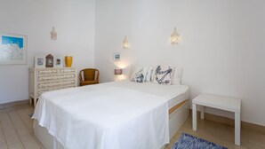 Quarto com cama grande, penteadeira, cadeira e mesa de cabeceira.