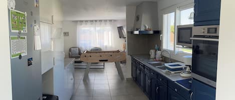 Una cocina moderna con estufa integrada, microondas y pileta. Hay un comedor con mesa y sillas.