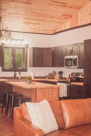 A kitchen with wooden cabinets, a stainless steel microwave, and a large island with stools. - Pet Friendly-Secluded-Fire Pit-300mbps internet (Brainerd)