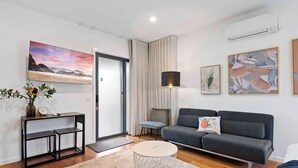 Una sala de estar moderna con un sofá gris, una mesa de centro, una mesita auxiliar con un jarrón y obras de arte en las paredes.