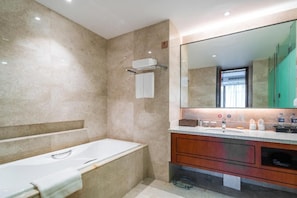 A modern bathroom with a bathtub, a large mirror, and a vanity with a sink.
