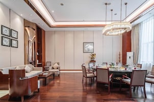 Un comedor amplio con una mesa redonda dispuesta para una comida, flanqueada por sillas, y un sofá en la zona de estar contigua.