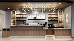 A modern café with a wooden reception desk, menu boards, and a coffee machine.