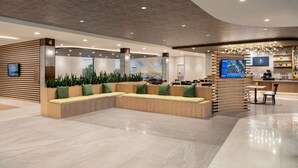 A modern lobby with a sectional sofa, a reception desk, and a large screen.