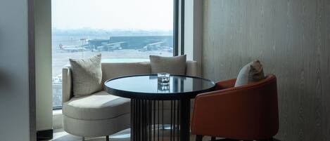 Una habitación moderna con una mesa redonda, dos sillas, un sofá y un amplio ventanal con vistas a la ciudad.