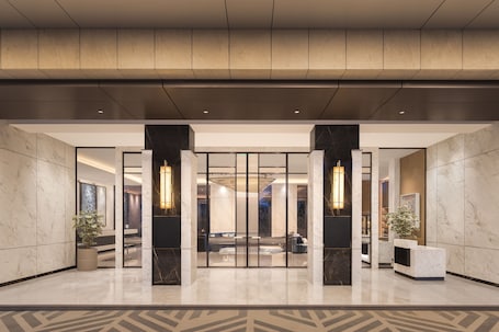 A modern lobby with marble flooring, a reception desk, and a seating area.