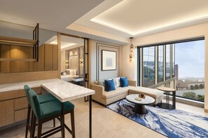 A modern living room with a sofa, a dining table, and a view of the city. - Fairfield by Marriott Mumbai International Airport (Mumbai)