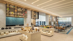 A modern hotel lobby with marble floors, a central reception desk, and a dining area with tables and chairs. - Fairfield by Marriott Mumbai International Airport (Mumbai)