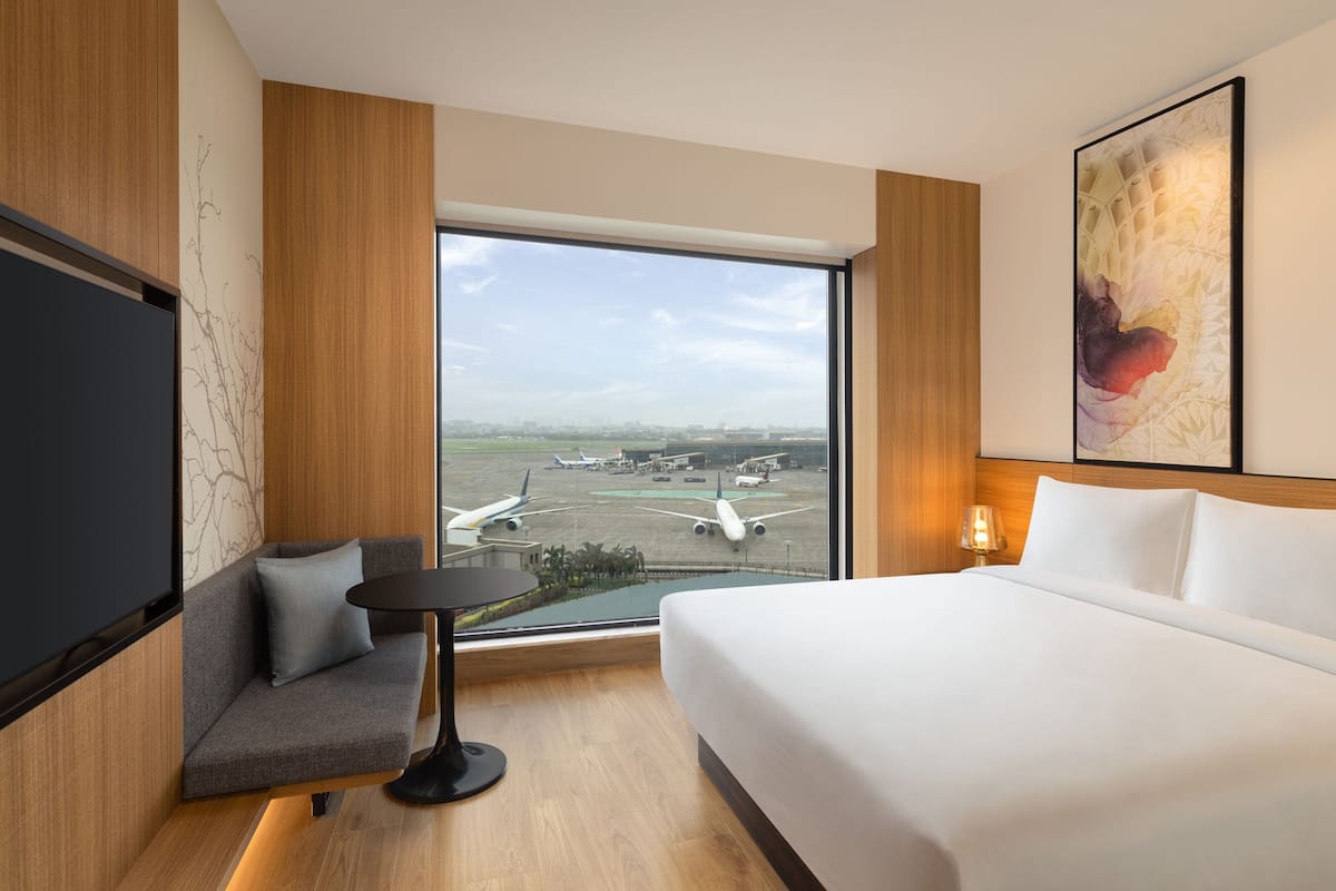Ein Hotelzimmer mit großem Fenster, einem Bett, einer Couch und einem kleinen Tisch.