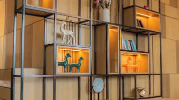A modern interior with a wooden wall panel, a metal shelving unit with decorative items, and a dining area with a table set for two.