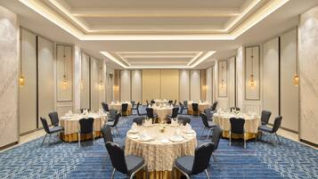 A conference room with round tables, chairs, and a carpeted floor.