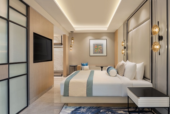 Una habitación de hotel moderna con una cama grande, un televisor de pantalla plana, una mesita de noche y un escritorio con una silla.