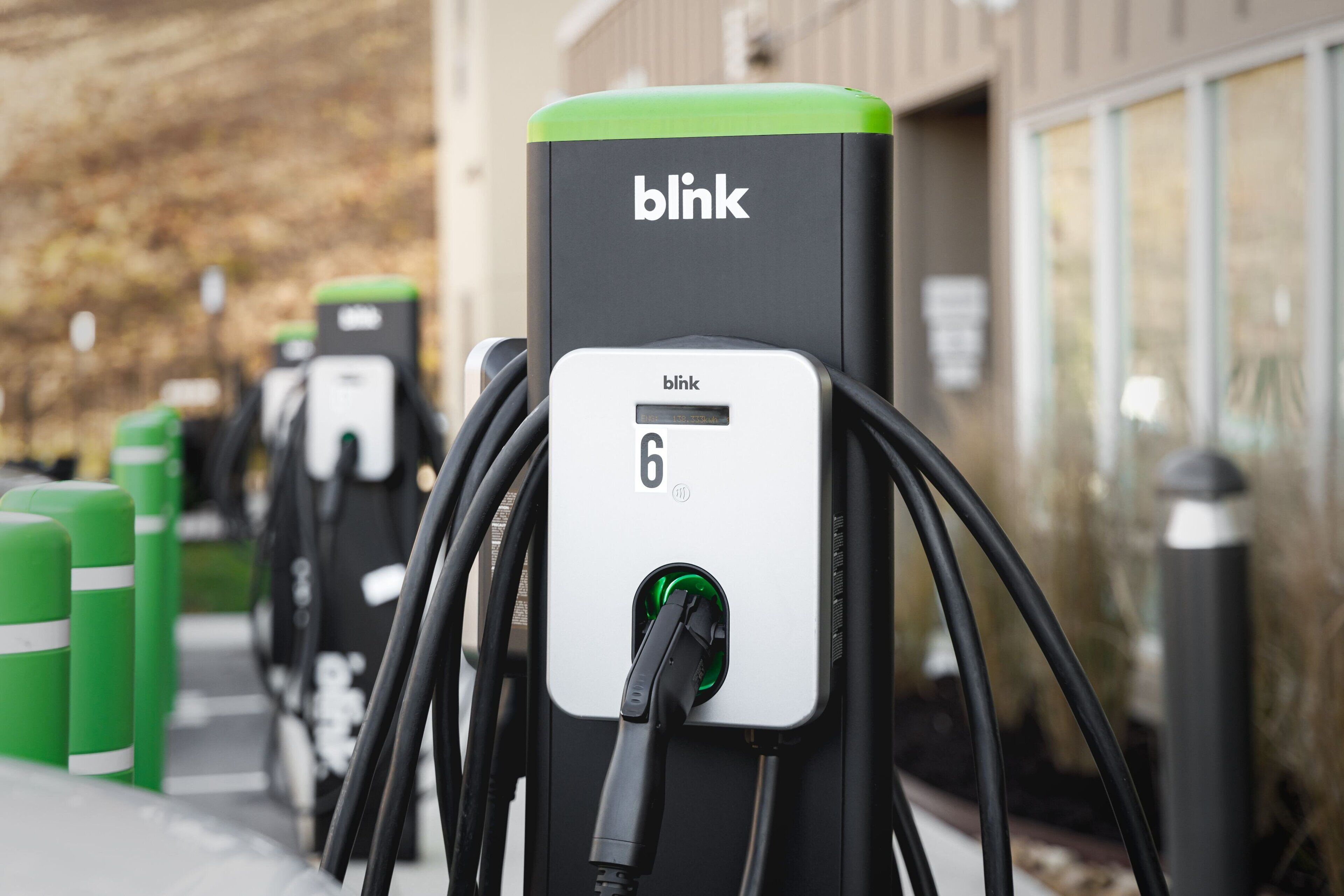 Una fila de estaciones de carga para vehículos eléctricos Blink, con pantalla digital.