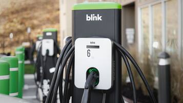 Una fila de estaciones de carga para vehículos eléctricos Blink, con pantalla digital.
