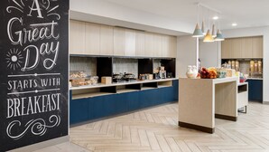 Une cuisine moderne dotée d’un bar pour prendre le petit-déjeuner, de meubles en bois et de luminaires suspendus.