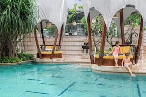 A pool area with a clear water surface, lounge chairs, and a seating area with a view of the surrounding greenery.