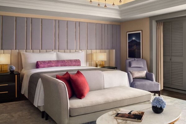 A hotel room with a large bed, a grey sofa, a chair, a nightstand, and a round coffee table. - The St. Regis Jakarta (Jakarta)