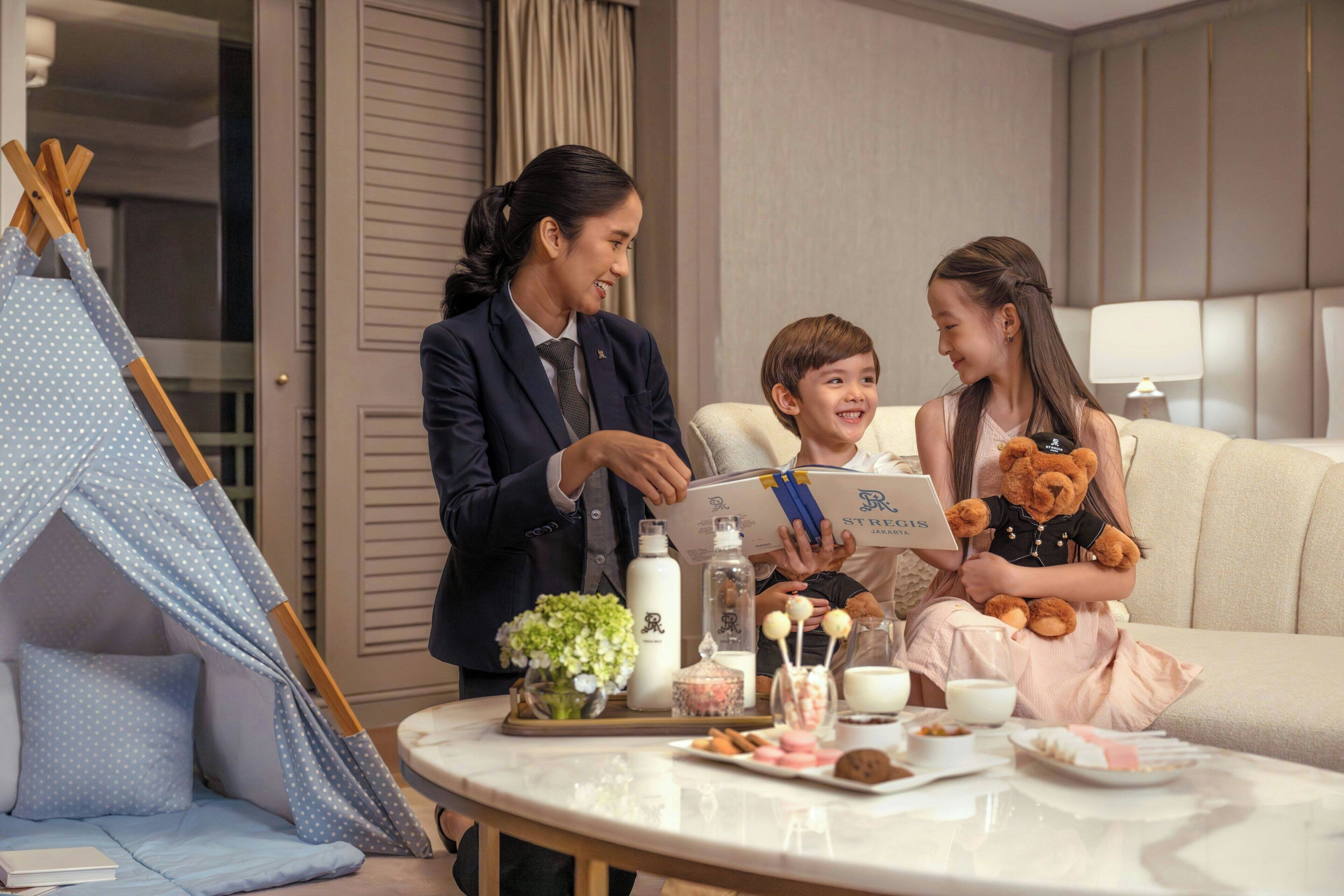 A room with a tent, a table with food and drinks, and a person holding a teddy bear.
