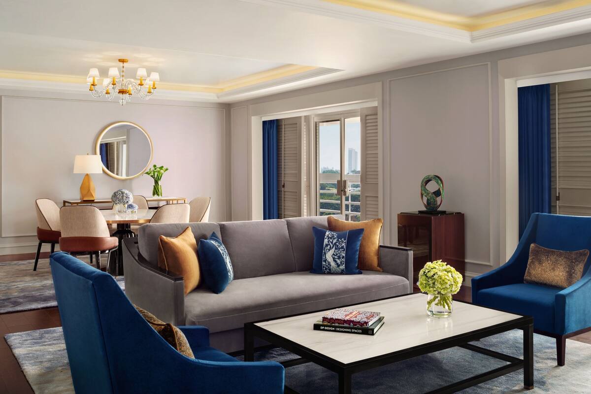 A modern living room with a grey sofa, blue armchairs, a coffee table, and a chandelier.