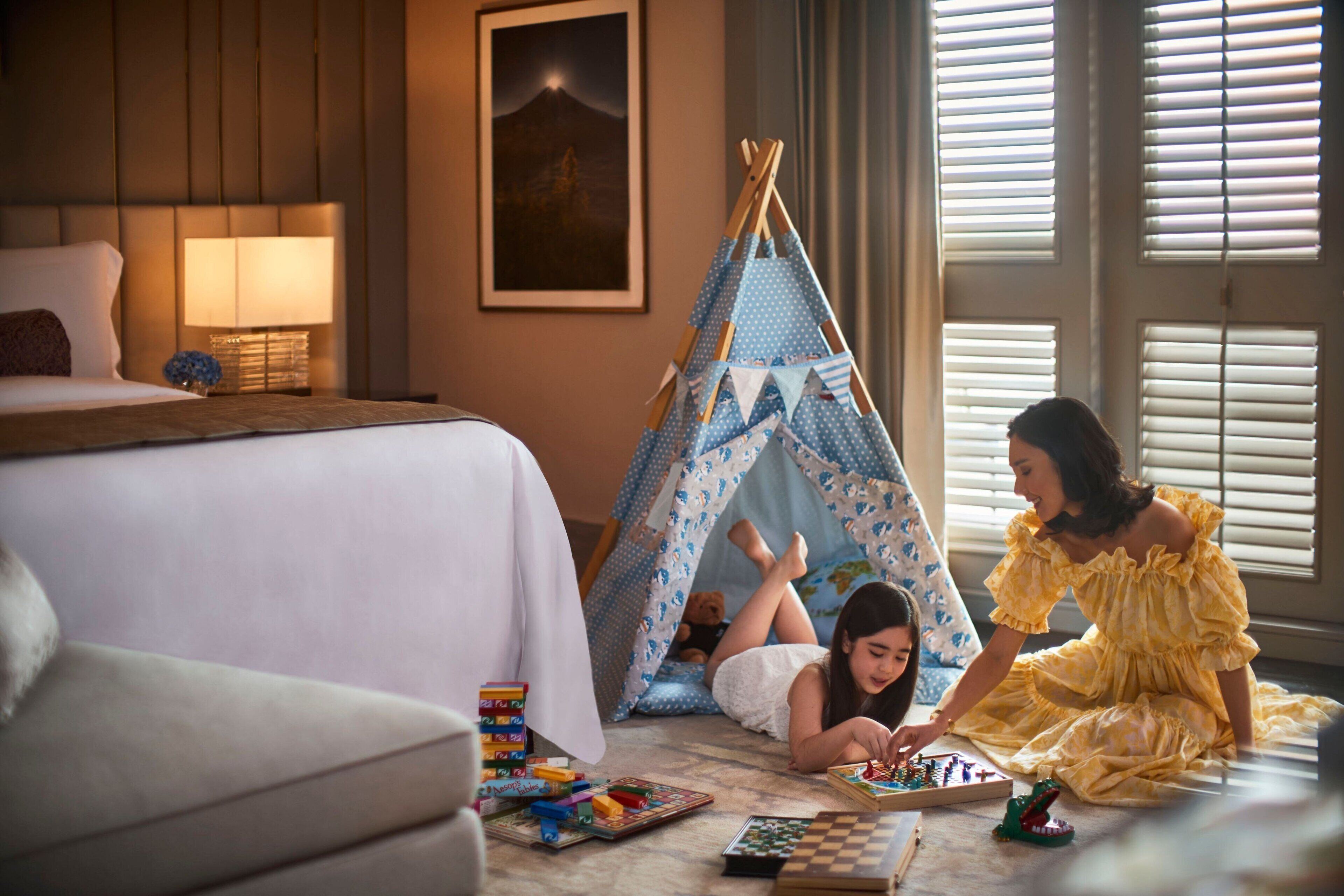 Un dormitorio con cama, mesita de noche, lámpara, tipi y ventana con persianas.
