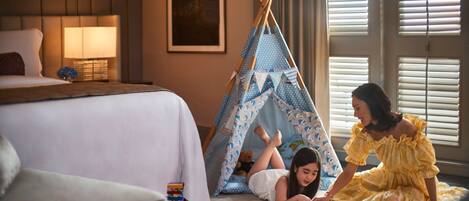 Un dormitorio con cama, mesita de noche, lámpara, tipi y ventana con persianas.