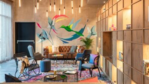 Una sala de estar moderna con un gran mural de pájaros, un sofá y una estantería.