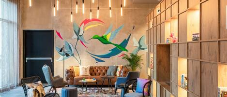 Una sala de estar moderna con un gran mural de pájaros, un sofá y una estantería.
