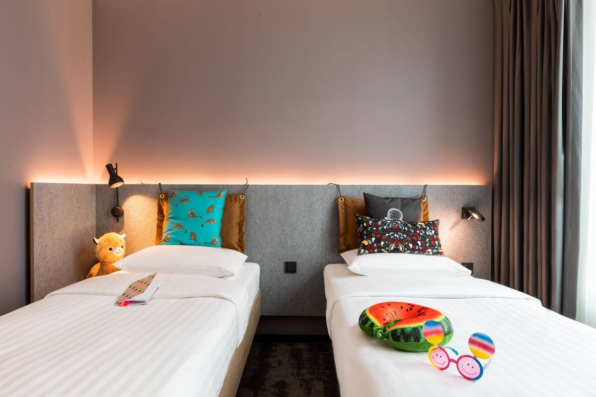 Habitació d'hotel amb dos llits, cada un amb un almoiner i una làmpada.