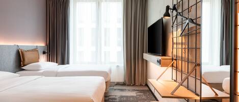 Una habitación de hotel con dos camas, televisión, escritorio y un amplio ventanal con cortinas.