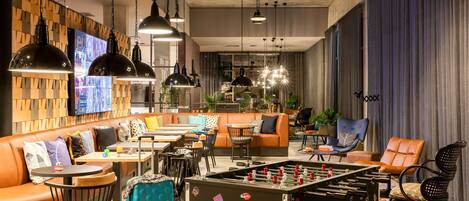 Un área de lounge moderna con mesa de fútbol, asientos cómodos e iluminación ambiental.