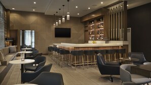 A modern bar area with a long counter, bar stools, and a television mounted on the wall. - Residence Inn by Marriott Oakland Downtown (Oakland)