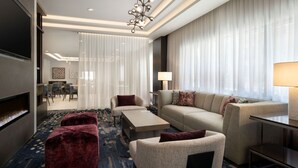 A modern hotel room with a sofa, armchairs, ottoman, and a flat-screen TV. - Residence Inn by Marriott Oakland Downtown (Oakland)
