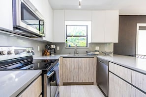 A modern kitchen with a built-in oven, microwave, and stove, a window with a view, and a sink.