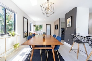 Un espace repas moderne avec une table en bois, des chaises bleues et une suspension au design géométrique.