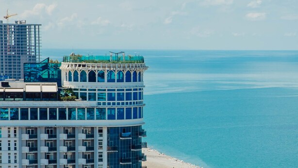 A high-rise hotel with a curved facade overlooking a beach and the sea. - ORBI CITY Hotel Sea View (Batumi)