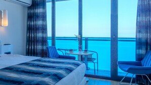 A hotel room with a large bed, a small table with chairs, and a balcony with a view of the sea. - ORBI CITY Hotel Sea View (Batumi)