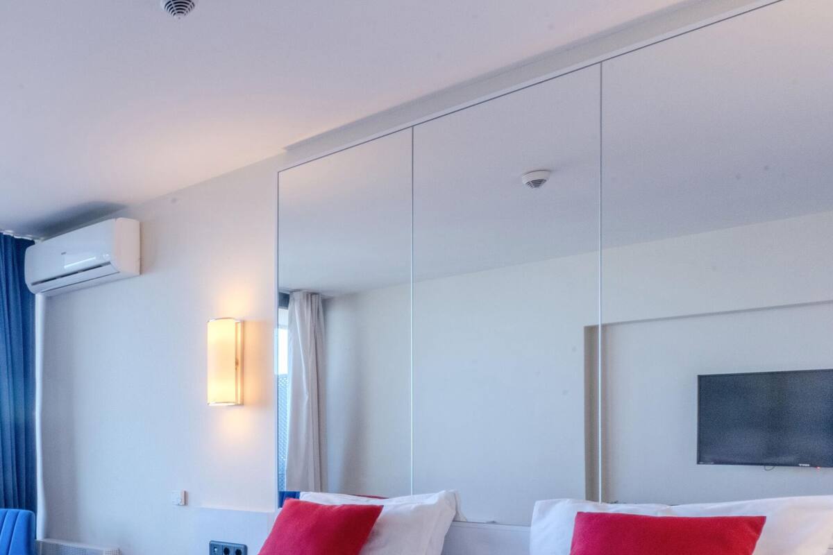 Ein Hotelzimmer mit einem großen Bett, einem Flachbildfernseher und einer wandmontierten Klimaanlage.