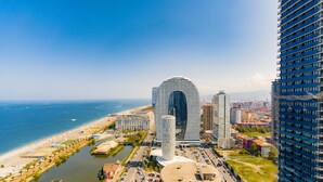 A modern urban area with a distinctive building featuring a curved top and a cylindrical structure in the foreground. - ORBI CITY Hotel Sea View (Batumi)